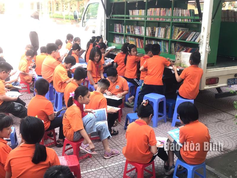 Một người trẻ đang ngồi trong thư viện hoặc phòng làm việc, say sưa nghiên cứu các tài liệu lịch sử, có thể cho lớp 11 hoặc cao hơn.